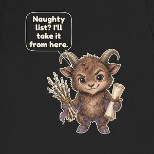 Puede incluir: Una camiseta negra con una criatura marr&oacute;n, peluda y con cuernos que sostiene un manojo de ramitas de abedul y un pergamino. Un globo de texto sobre la criatura contiene el texto: Naughty list? I'll take it from here. El dise&ntilde;o est&aacute; centrado.