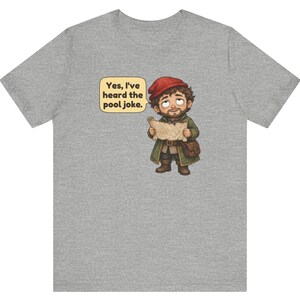 May include: A heather grey t-shirt featuring a cartoon illustration of a bearded character wearing a red cap and green coat, holding a map. A speech bubble next to the character contains the text: Yes, I've heard the pool joke.