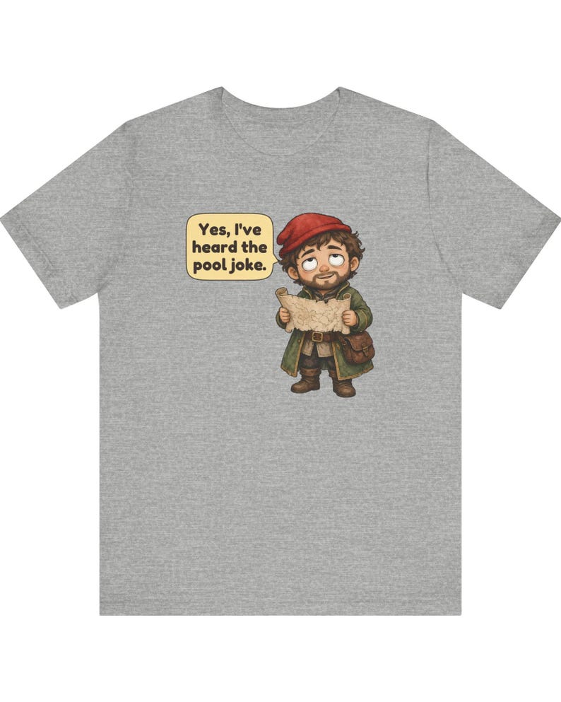 May include: A heather grey t-shirt featuring a cartoon illustration of a bearded character wearing a red cap and green coat, holding a map. A speech bubble next to the character contains the text: Yes, I've heard the pool joke.