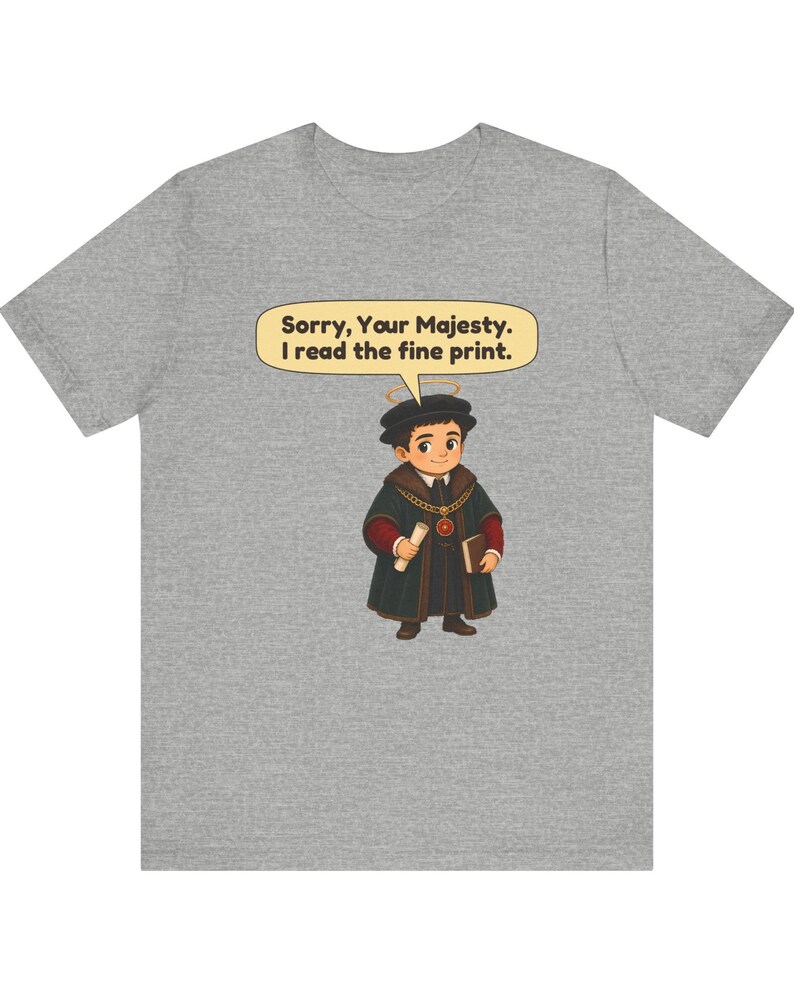May include: A heather gray t-shirt featuring a cartoon illustration of a person wearing a dark robe, a gold chain, and a halo. The person holds a scroll and a book. A speech bubble above contains the text: Sorry, Your Majesty. I read the fine print.