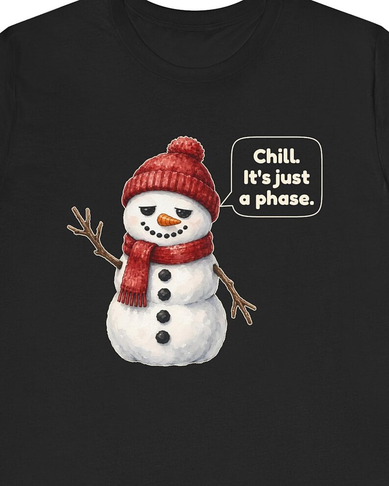 Pode incluir: Uma t-shirt preta com um gr&aacute;fico de um boneco de neve branco a usar um gorro e um cachecol de malha vermelhos. O boneco de neve tem bra&ccedil;os de pau, nariz de cenoura e bot&otilde;es de carv&atilde;o. Um bal&atilde;o de fala cont&eacute;m o texto, Chill. It's just a phase.