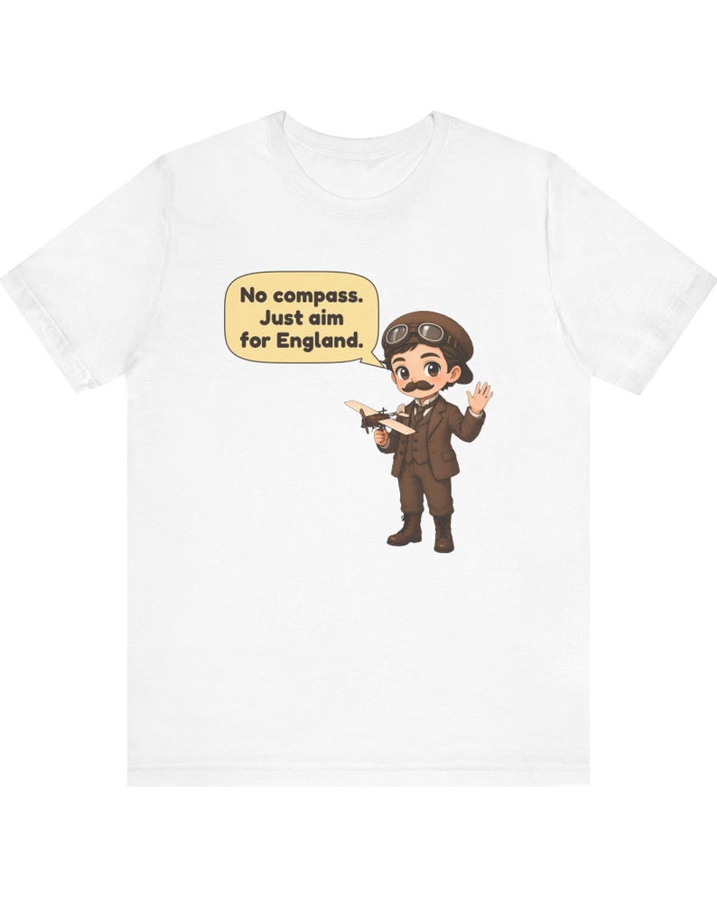 May include: A white t-shirt featuring a cartoon illustration of an aviator with a mustache, goggles, and a brown suit holding a small airplane. A speech bubble contains the text: No compass. Just aim for England.