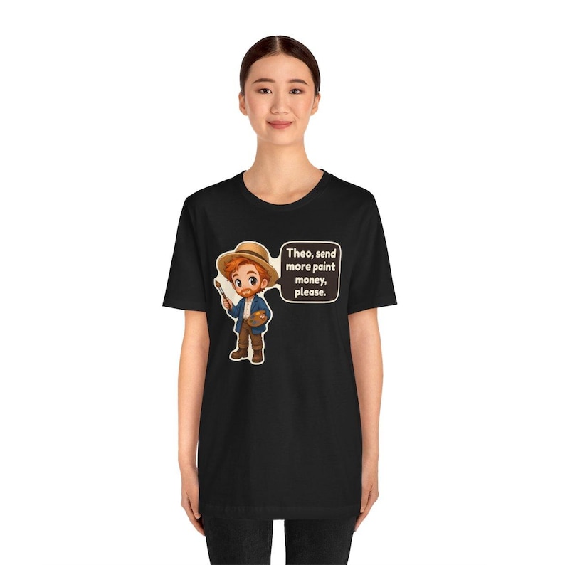 May include: A black t-shirt featuring a cartoon illustration of a red-haired artist wearing a straw hat, holding a paintbrush and palette. A speech bubble next to the character contains the text: Theo, send more paint money, please.