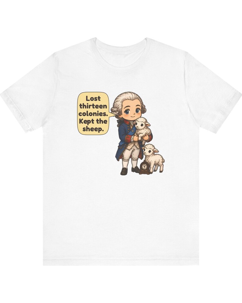 Peut inclure: Un t-shirt blanc avec une illustration de style dessin anim&eacute; repr&eacute;sentant un personnage historique en manteau bleu et perruque blanche tenant un agneau, avec un autre agneau et une petite horloge. Une bulle contient le texte : Lost thirteen colonies. Kept the sheep.