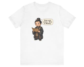 May include: A white t-shirt featuring a cartoon illustration of a person with a topknot hairstyle wearing dark robes and holding a bamboo scroll. A speech bubble next to the character contains the text: Know your enemy. Mine is Monday.