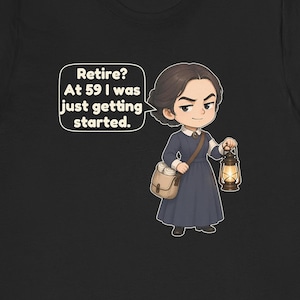 May include: A black t-shirt featuring a cartoon illustration of a person in a dark blue dress with a white collar, carrying a tan satchel and a lit lantern. A speech bubble contains the text: Retire? At 59 I was just getting started.