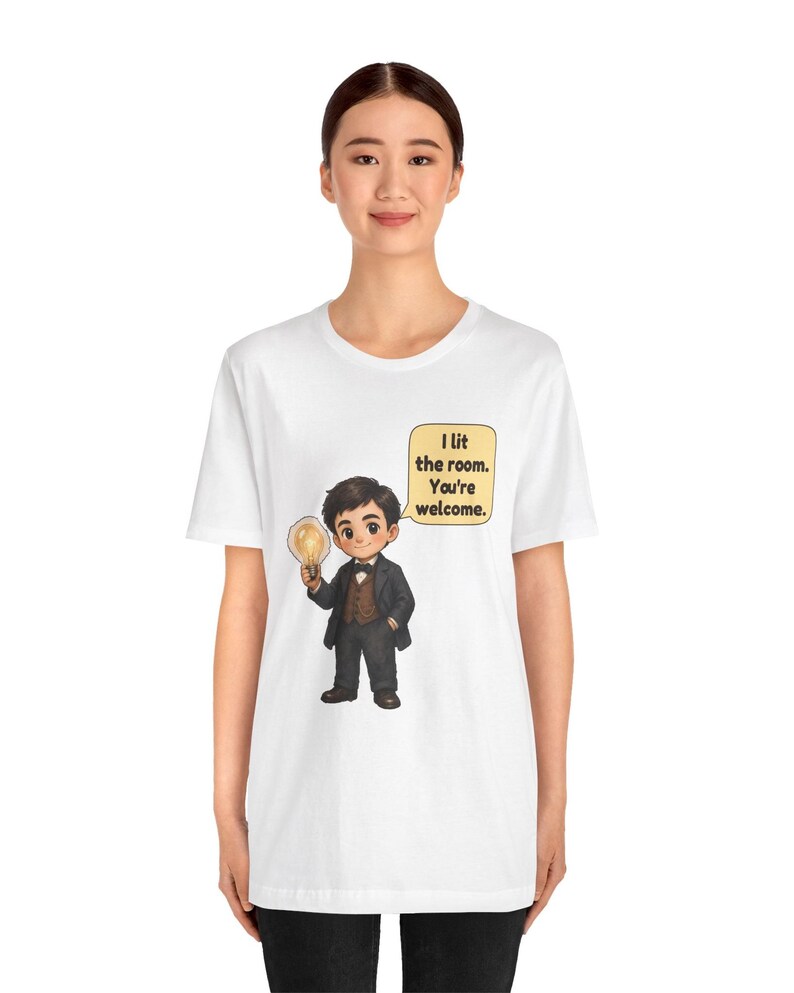 Może przedstawiać: Biały t-shirt z rysunkową ilustracją osoby w ciemnym garniturze i brązowej kamizelce, trzymającej świecącą żar&oacute;wkę. Dymek zawiera tekst: I lit the room. You're welcome.