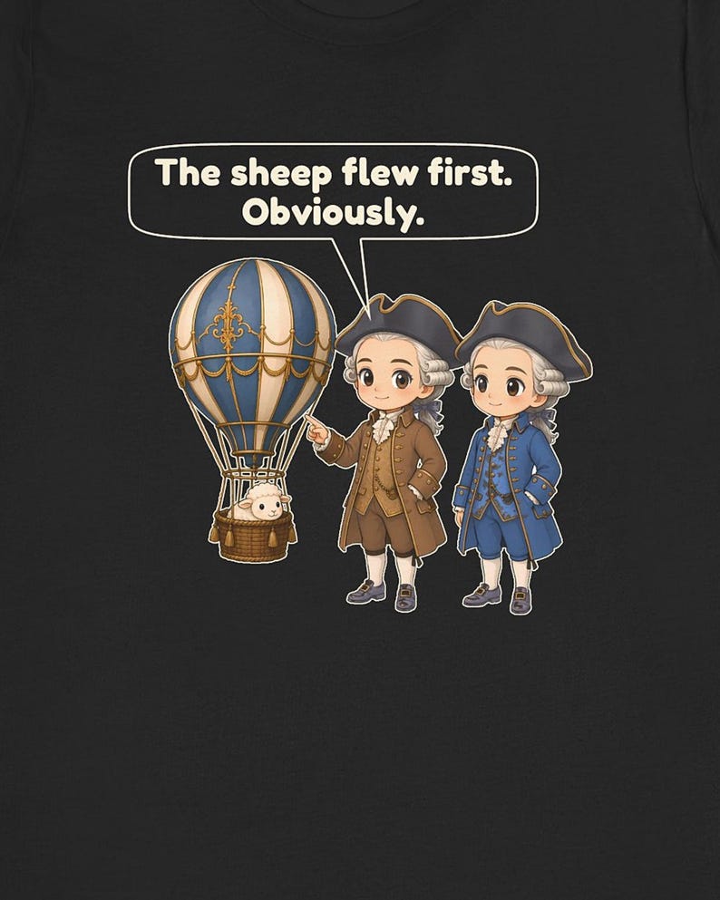 May include: A black t-shirt featuring a graphic of two figures in 18th-century attire standing next to a blue and white hot air balloon with a sheep in the basket. A speech bubble above contains the text: The sheep flew first. Obviously.