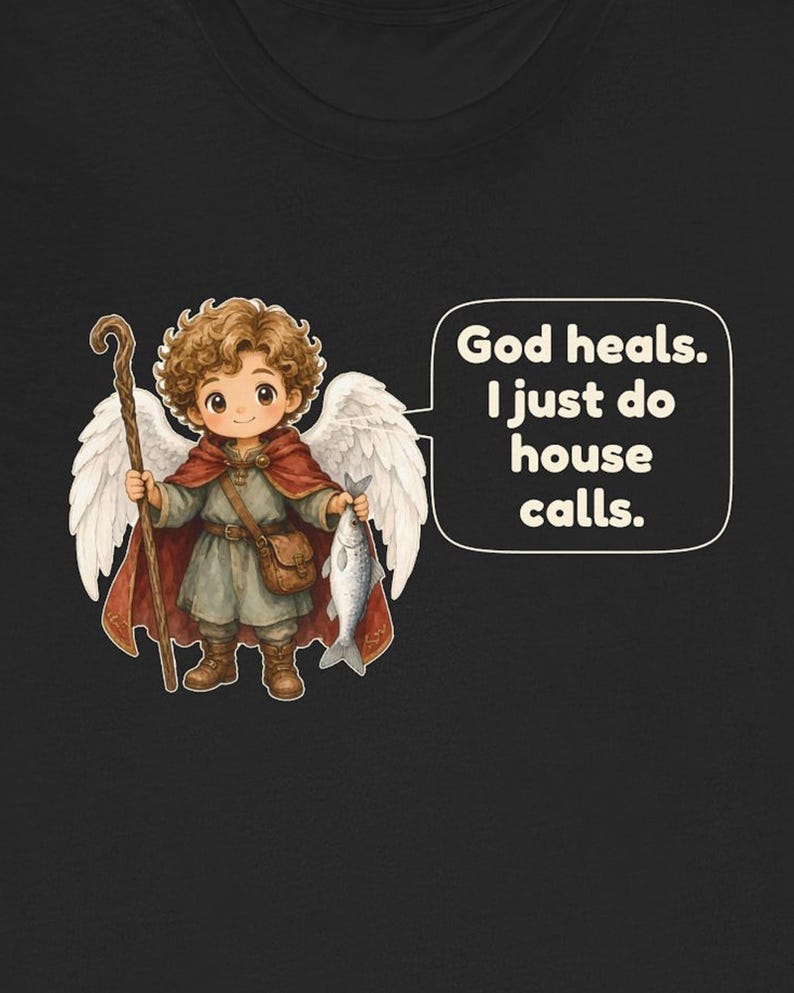 May include: A black t-shirt featuring a cartoon angel with curly brown hair, white wings, a red cloak, and a brown tunic. The angel holds a wooden staff and a silver fish. A speech bubble contains the text: God heals. I just do house calls.
