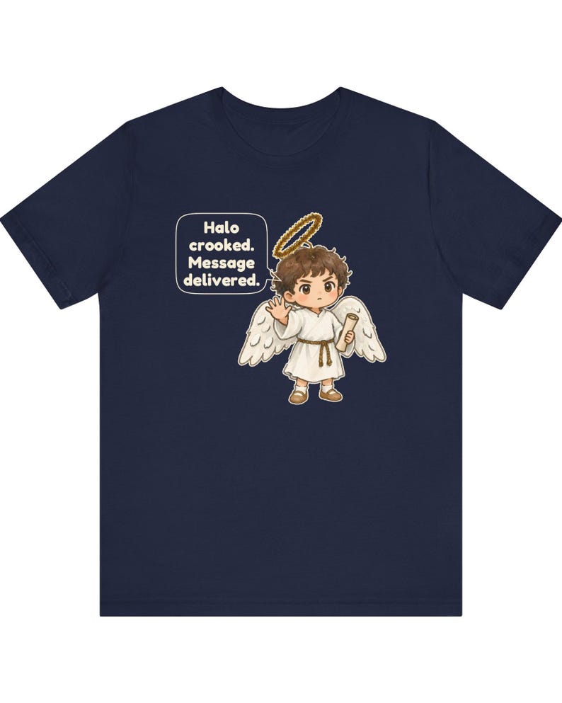 May include: A navy blue t-shirt featuring a graphic of a cartoon angel with brown hair, white wings, and a gold halo. The angel holds a scroll and waves. A speech bubble contains the text: Halo crooked. Message delivered.