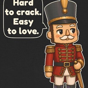 Pu&ograve; includere: Una figura di schiaccianoci in stile cartoon che indossa un'uniforme rossa con dettagli dorati, un alto cappello nero e pantaloni bianchi. Un fumetto accanto alla figura contiene il testo: Hard to crack. Easy to love. Il design &egrave; su sfondo scuro.