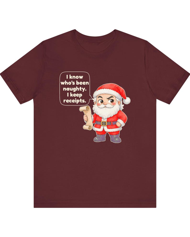 May include: A maroon short-sleeve t-shirt featuring a cartoon Santa Claus holding a scroll. A speech bubble above Santa contains the text: I know who's been naughty. I keep receipts. The graphic is centered on the front of the shirt.
