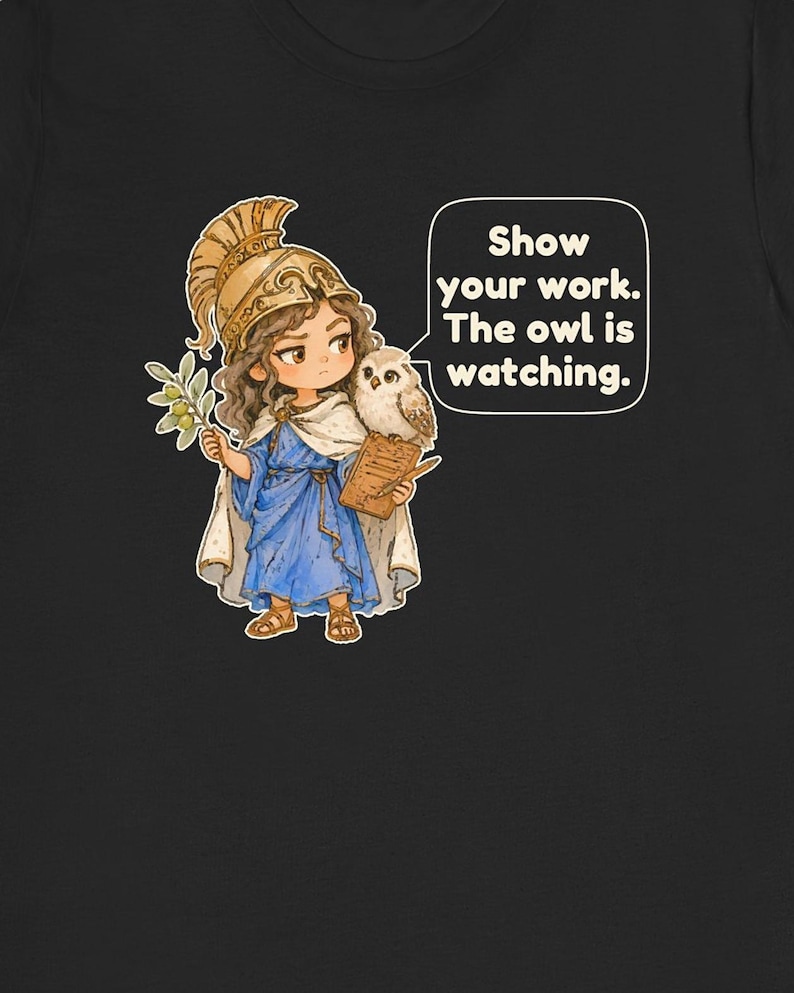 Puede incluir: Una camiseta negra con una ilustraci&oacute;n de dibujos animados de una figura con casco dorado y t&uacute;nica azul que sostiene una rama de olivo y un portapapeles con un b&uacute;ho en el brazo. Un globo de texto contiene: Show your work. The owl is watching.