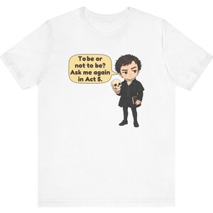 以下が含まれることがあります： 白いTシャツに、暗い色の服を着て頭蓋骨を持っているキャラクターの漫画風イラストが描かれています。キャラクターの横にある吹き出しには「To be or not to be? Ask me again in Act 5.」というテキストが含まれています。デザインは中央に配置されています。