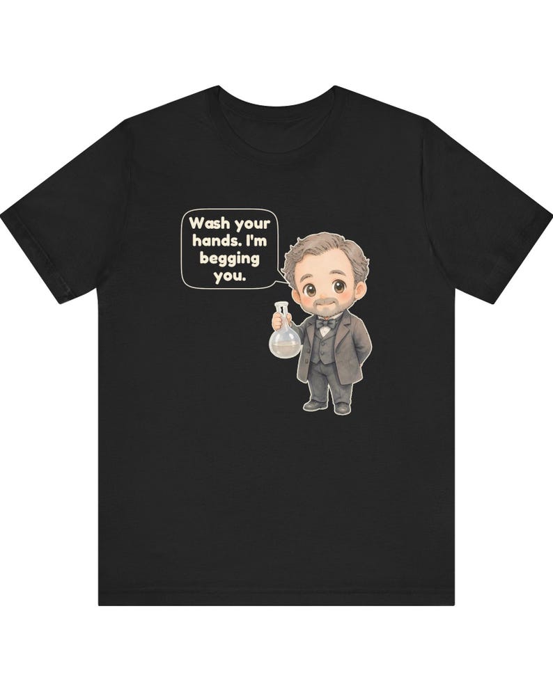 May include: A black t-shirt featuring a cartoon illustration of a man in a suit holding a glass flask. A speech bubble next to him contains the text: Wash your hands. I'm begging you. The design is centered on the front of the garment.