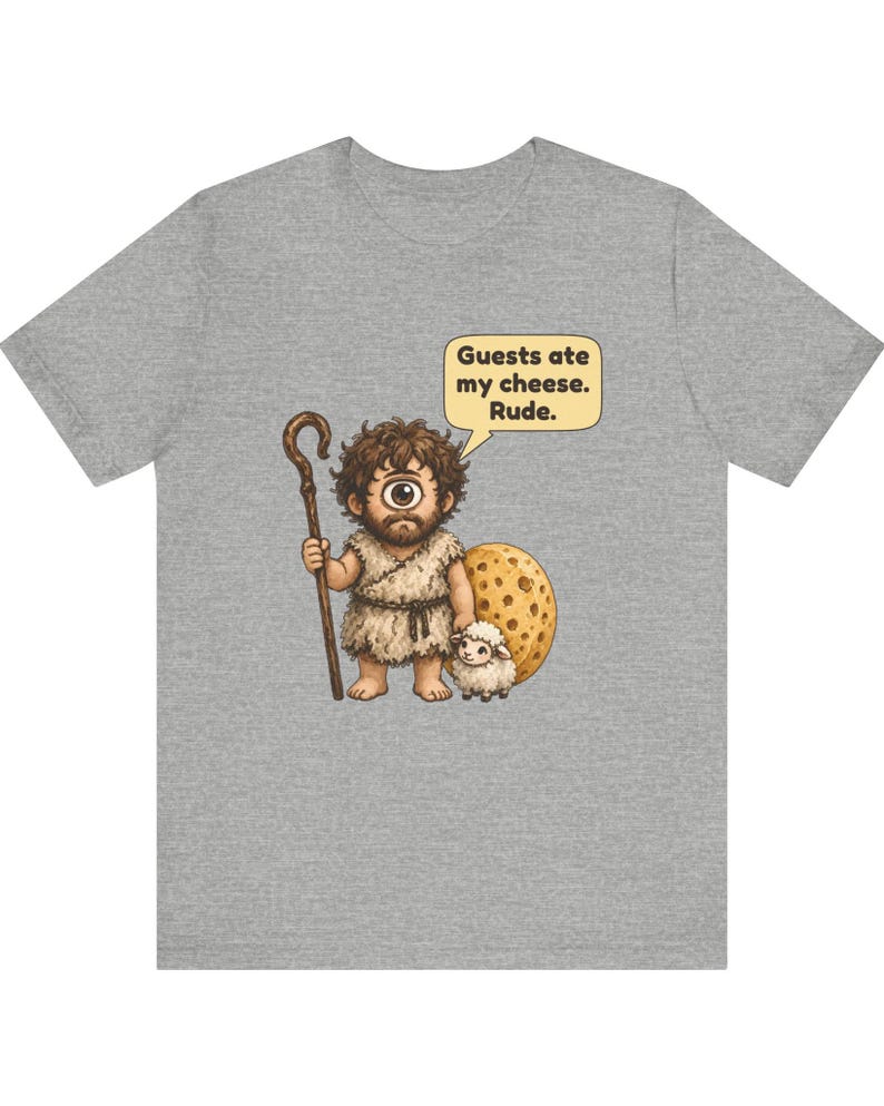 May include: A heather gray t-shirt featuring a cartoon cyclops with a brown wooden staff and a small white sheep. The cyclops stands next to a large round piece of yellow Swiss cheese. A speech bubble contains the text: Guests ate my cheese. Rude.