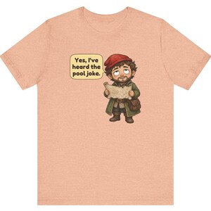 May include: A peach-coloured t-shirt featuring a cartoon illustration of a bearded character in a red cap and green coat holding a map. A speech bubble above the character contains the text, "Yes, I've heard the pool joke."