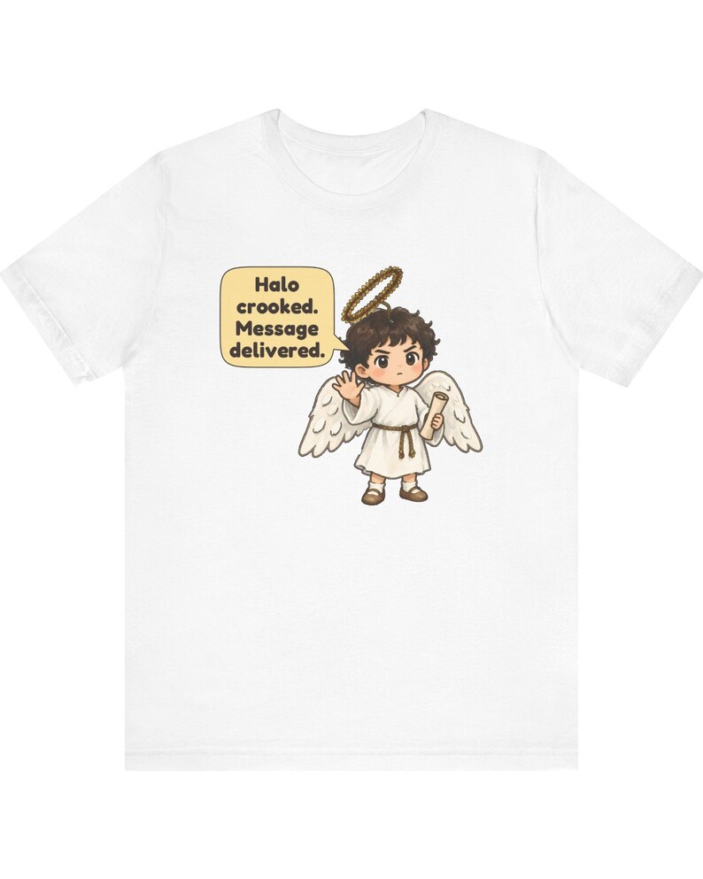 May include: A white t-shirt featuring a graphic of a cartoon angel with dark hair, white wings, and a crooked halo. The angel holds a scroll and waves, with a speech bubble containing the text: Halo crooked. Message delivered.