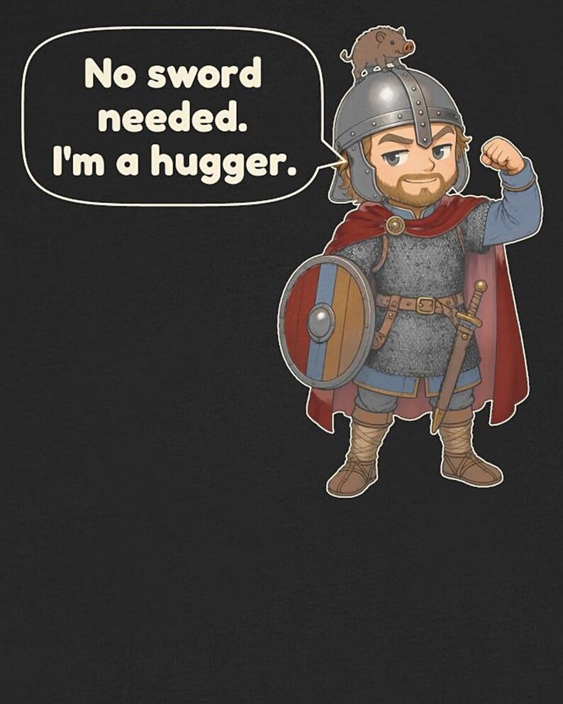 May include: A black t-shirt featuring a cartoon warrior in chainmail armor, a red cape, and a helmet with a small boar on top. The warrior holds a shield and flexes an arm. A speech bubble contains the text: No sword needed. I'm a hugger.