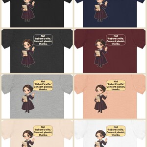 Puede incluir: Una colecci&oacute;n de ocho camisetas de varios colores con una ilustraci&oacute;n de dibujos animados de una persona con un vestido oscuro sosteniendo un libro, con un bocadillo que dice: Not 'Robert's wife.' Concert pianist, thanks.