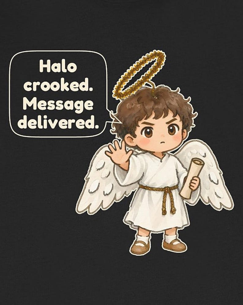May include: A black t-shirt featuring a cartoon angel with brown hair, white wings, and a gold halo. The angel wears a white robe with a brown rope belt and brown shoes, holding a scroll. A speech bubble contains the text: Halo crooked. Message delivered.
