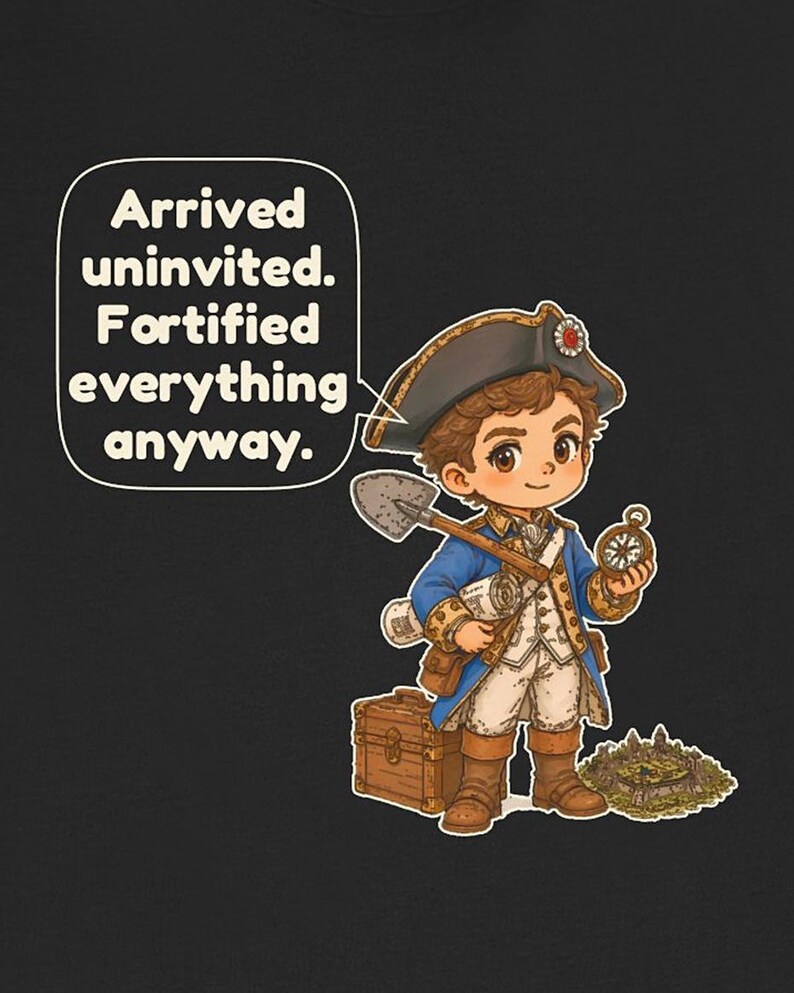 May include: A black t-shirt featuring a cartoon character in a blue and white 18th-century military uniform, holding a shovel and compass. A speech bubble contains the text: Arrived uninvited. Fortified everything anyway. A wooden chest and a small fortress are nearby.