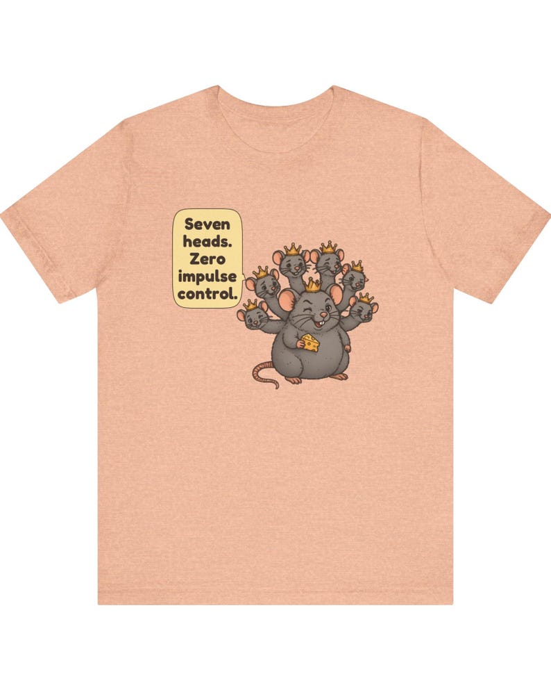 May include: A peach-colored t-shirt featuring a graphic of a gray seven-headed rat wearing small gold crowns and holding a piece of yellow cheese. A speech bubble next to the rat contains the text: Seven heads. Zero impulse control.