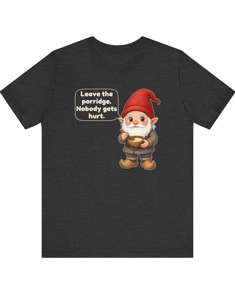 May include: A dark charcoal grey t-shirt featuring a graphic of a gnome wearing a red hat and brown clothing, holding a wooden bowl and spoon. A speech bubble next to the gnome contains the text: Leave the porridge. Nobody gets hurt.