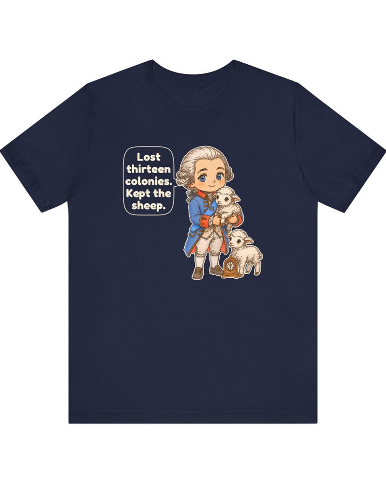 Peut inclure: Un t-shirt bleu marine avec une illustration de style dessin anim&eacute; repr&eacute;sentant une personne en tenue du XVIIIe si&egrave;cle tenant un agneau, avec un autre agneau et une petite horloge. Une bulle contient le texte : Lost thirteen colonies. Kept the sheep.