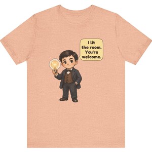 Może przedstawiać: Brzoskwiniowy t-shirt z rysunkową ilustracją osoby w ciemnym garniturze i muszce, trzymającej świecącą żar&oacute;wkę. Dymek obok postaci zawiera tekst: I lit the room. You're welcome.