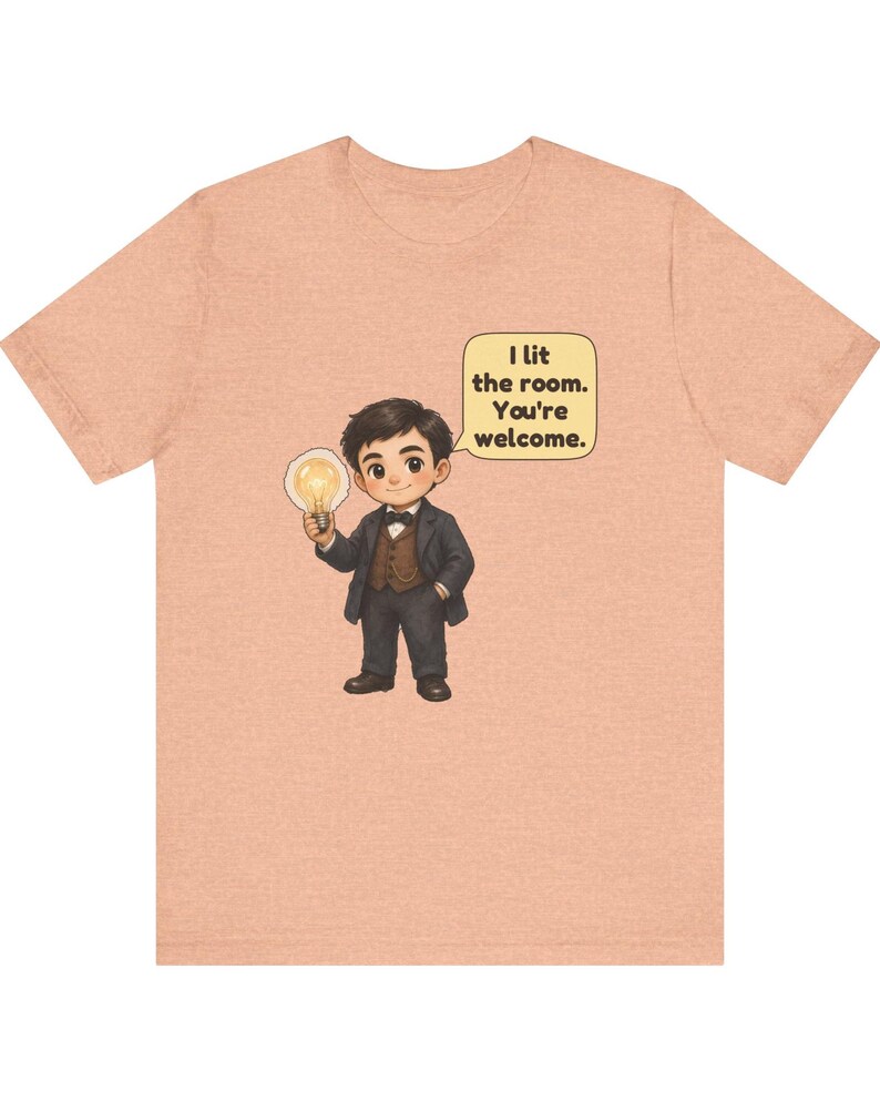 Może przedstawiać: Brzoskwiniowy t-shirt z rysunkową ilustracją osoby w ciemnym garniturze i muszce, trzymającej świecącą żar&oacute;wkę. Dymek obok postaci zawiera tekst: I lit the room. You're welcome.