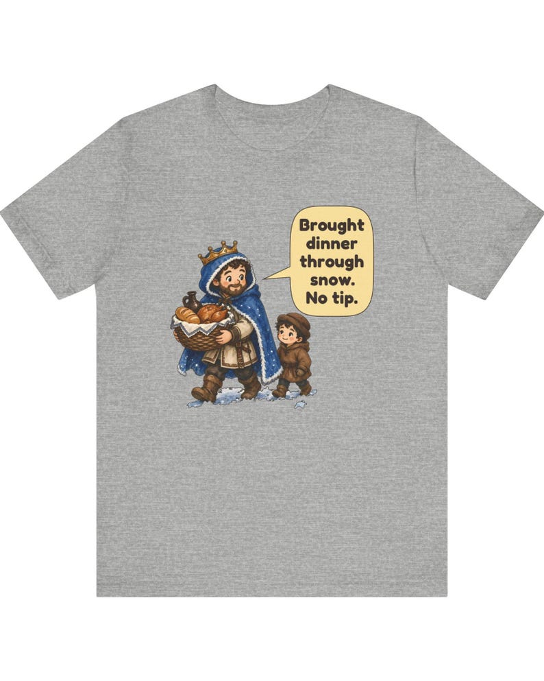 May include: A heather gray t-shirt featuring a cartoon illustration of a king in a blue cloak carrying a basket of bread and a child walking in snow. A speech bubble contains the text: Brought dinner through snow. No tip.