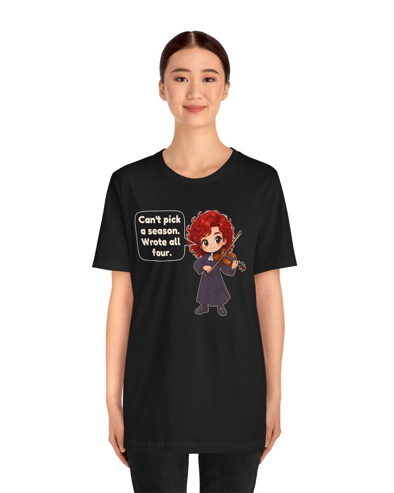 May include: A black t-shirt featuring a cartoon illustration of a red-haired violinist in a dark robe playing a violin. A speech bubble next to the character contains the text: Can't pick a season. Wrote all four.