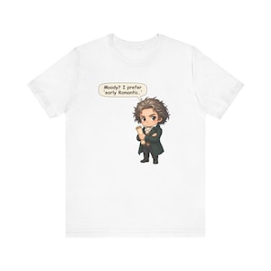 May include: A white short-sleeved t-shirt featuring a chibi-style illustration of a man with messy dark hair wearing a dark coat and holding a scroll. A speech bubble above the character contains the text: Moody? I prefer 'early Romantic.'