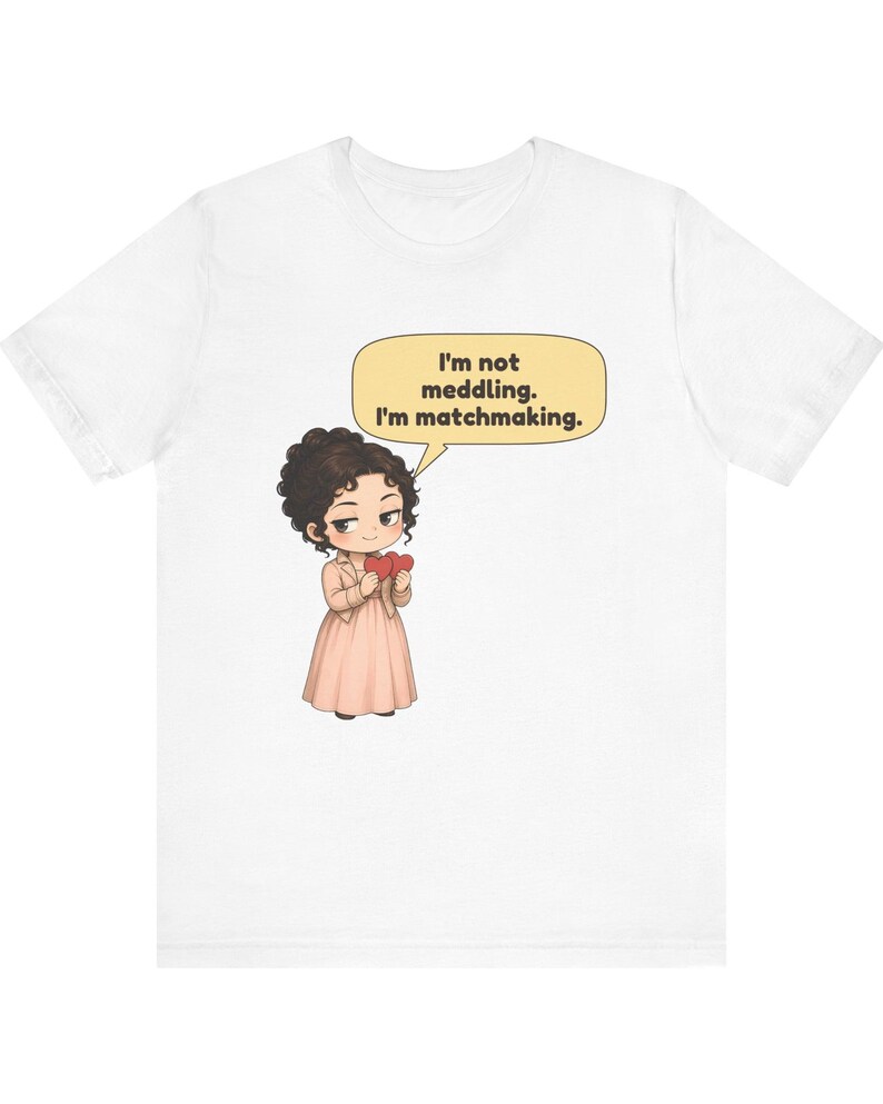 K&ouml;nnte beinhalten: Ein wei&szlig;es T-Shirt mit einer Cartoon-Illustration einer Person mit dunklem, lockigem Haar, die ein hellrosa Kleid und eine Jacke tr&auml;gt und zwei rote Herzen h&auml;lt. Eine gelbe Sprechblase dar&uuml;ber enth&auml;lt den Text: I'm not meddling. I'm matchmaking.