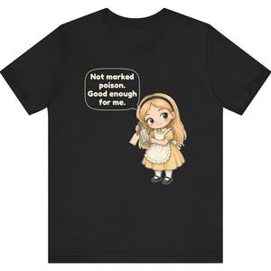 May include: A black t-shirt featuring a cartoon illustration of a blonde girl in a yellow dress and white apron holding a glass bottle. A speech bubble above her contains the text: Not marked poison. Good enough for me.