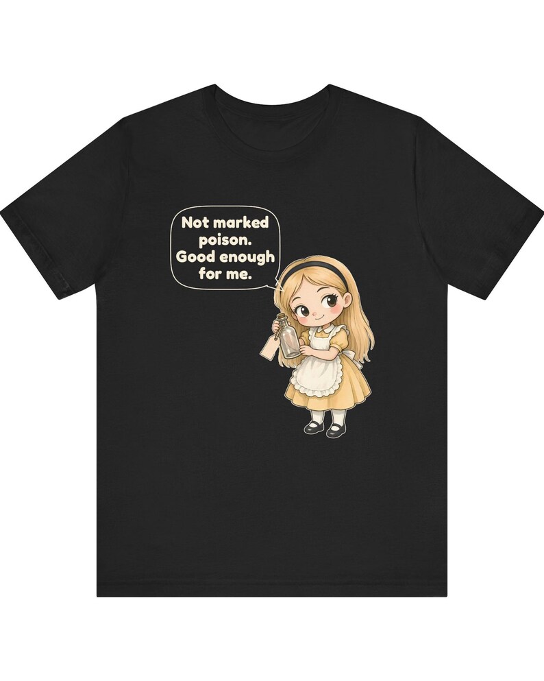 May include: A black t-shirt featuring a cartoon illustration of a blonde girl in a yellow dress and white apron holding a glass bottle. A speech bubble above her contains the text: Not marked poison. Good enough for me.