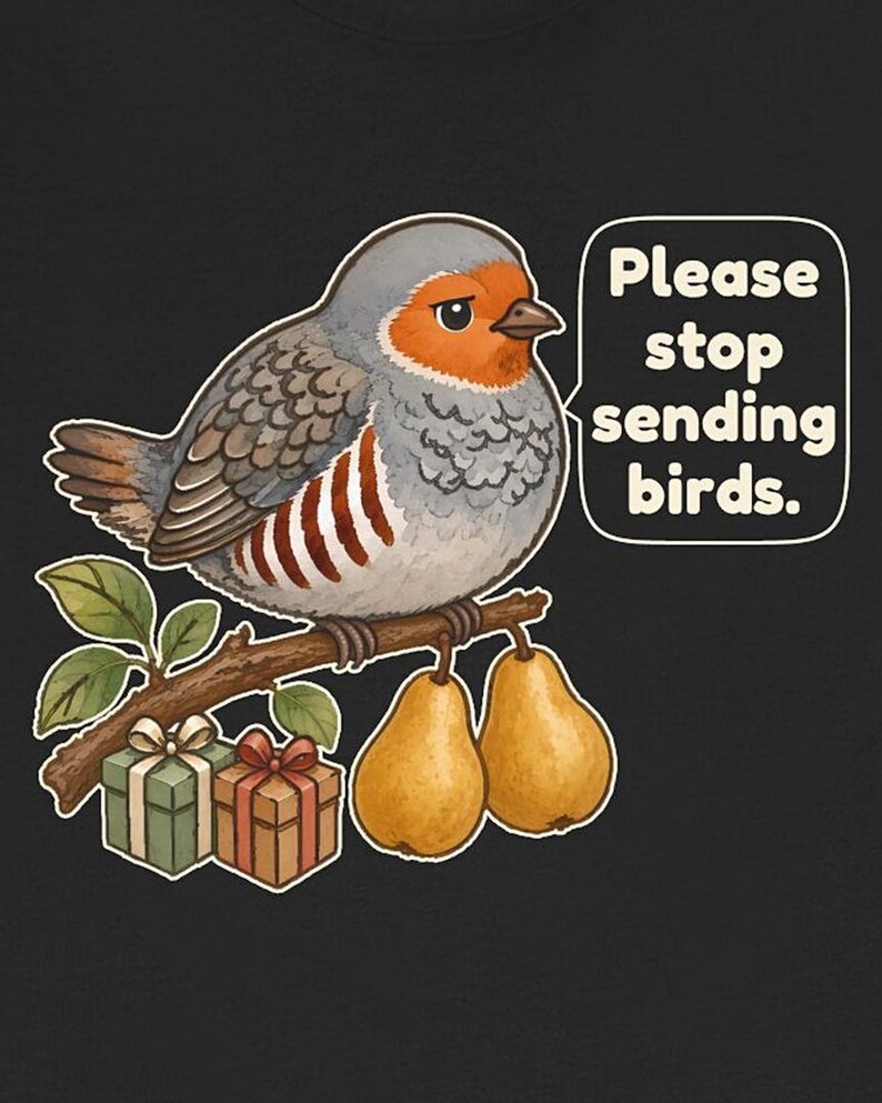 K&ouml;nnte beinhalten: Ein schwarzes T-Shirt-Motiv mit einem grauen und orangefarbenen Vogel auf einem braunen Ast, zwei gelben Birnen und zwei kleinen Geschenken. Eine wei&szlig;e Sprechblase enth&auml;lt den schwarzen Text: Please stop sending birds.