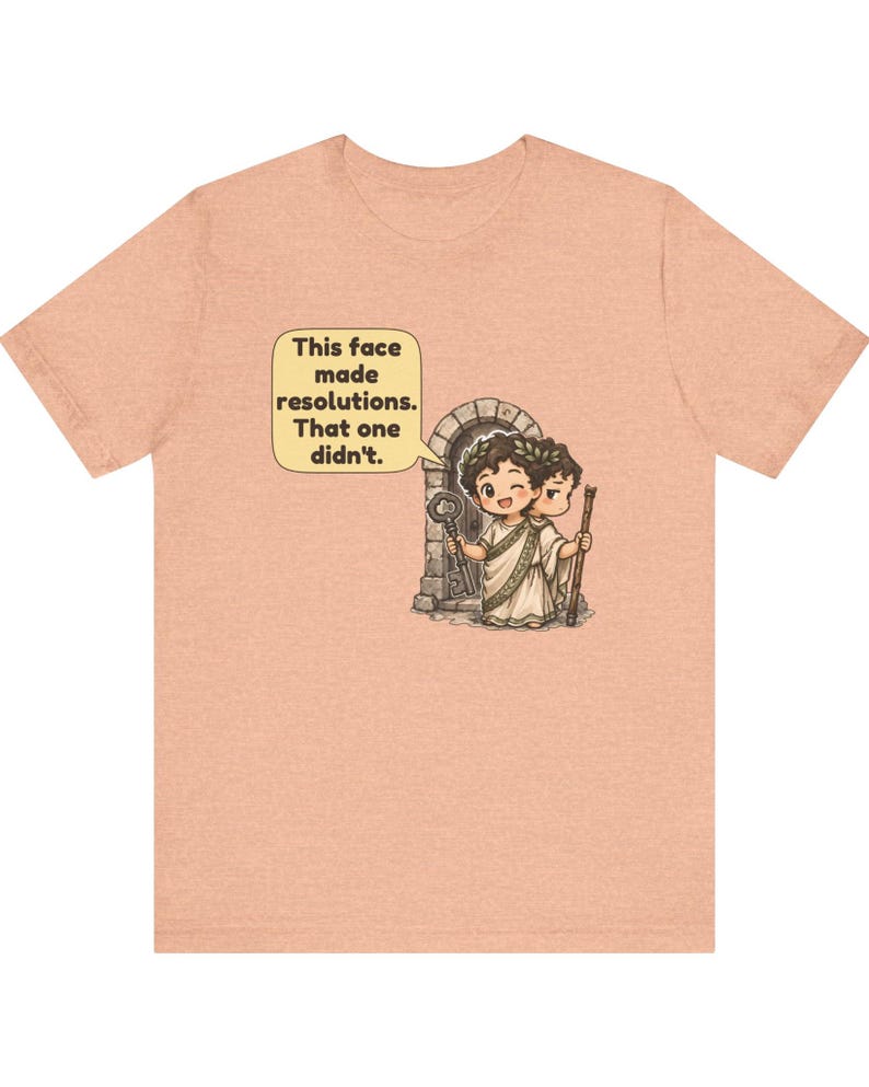 K&ouml;nnte beinhalten: Ein pfirsichfarbenes T-Shirt mit einer Grafik des zweigesichtigen r&ouml;mischen Gottes Janus, der einen Lorbeerkranz tr&auml;gt. Ein Gesicht zwinkert und h&auml;lt einen Schl&uuml;ssel, das andere wirkt streng. Eine Sprechblase enth&auml;lt den Text: This face made resolutions. That one didn't.