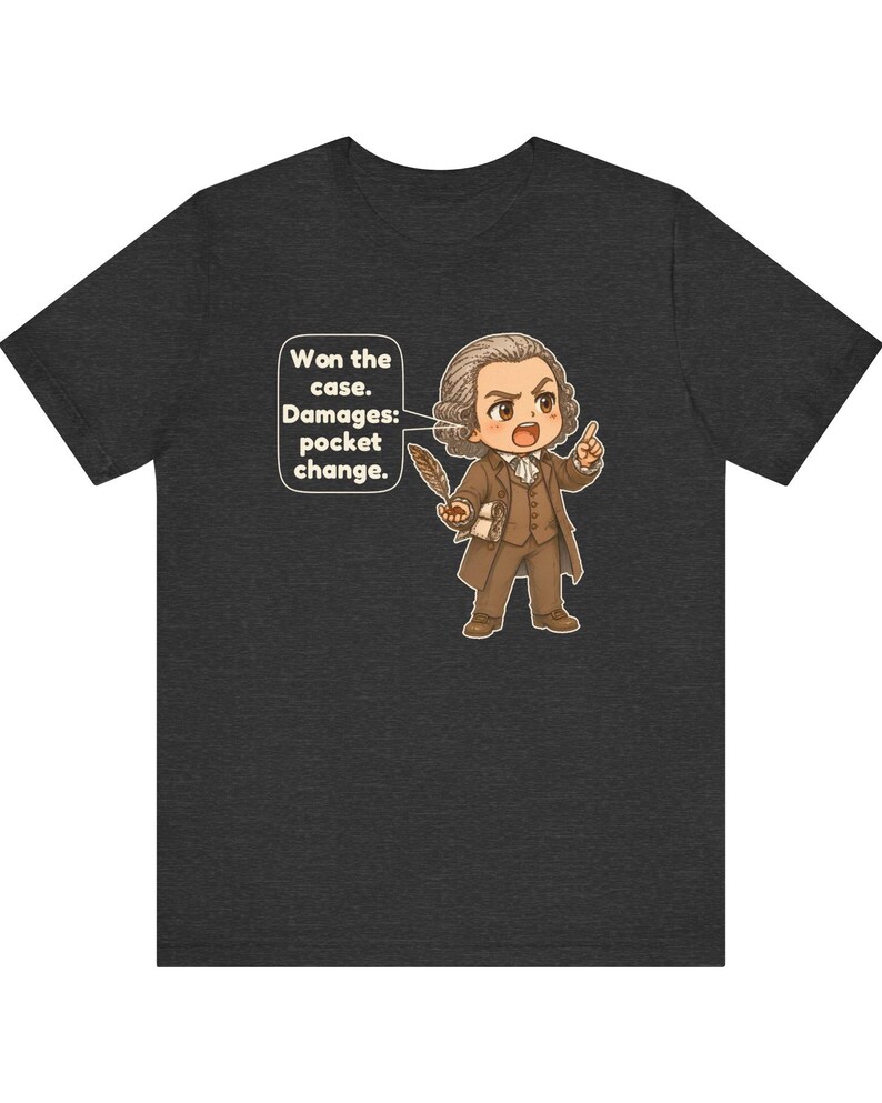 May include: A dark heather gray t-shirt featuring a cartoon illustration of a lawyer in a brown suit holding a quill. A speech bubble next to the character contains the text: Won the case. Damages: pocket change.