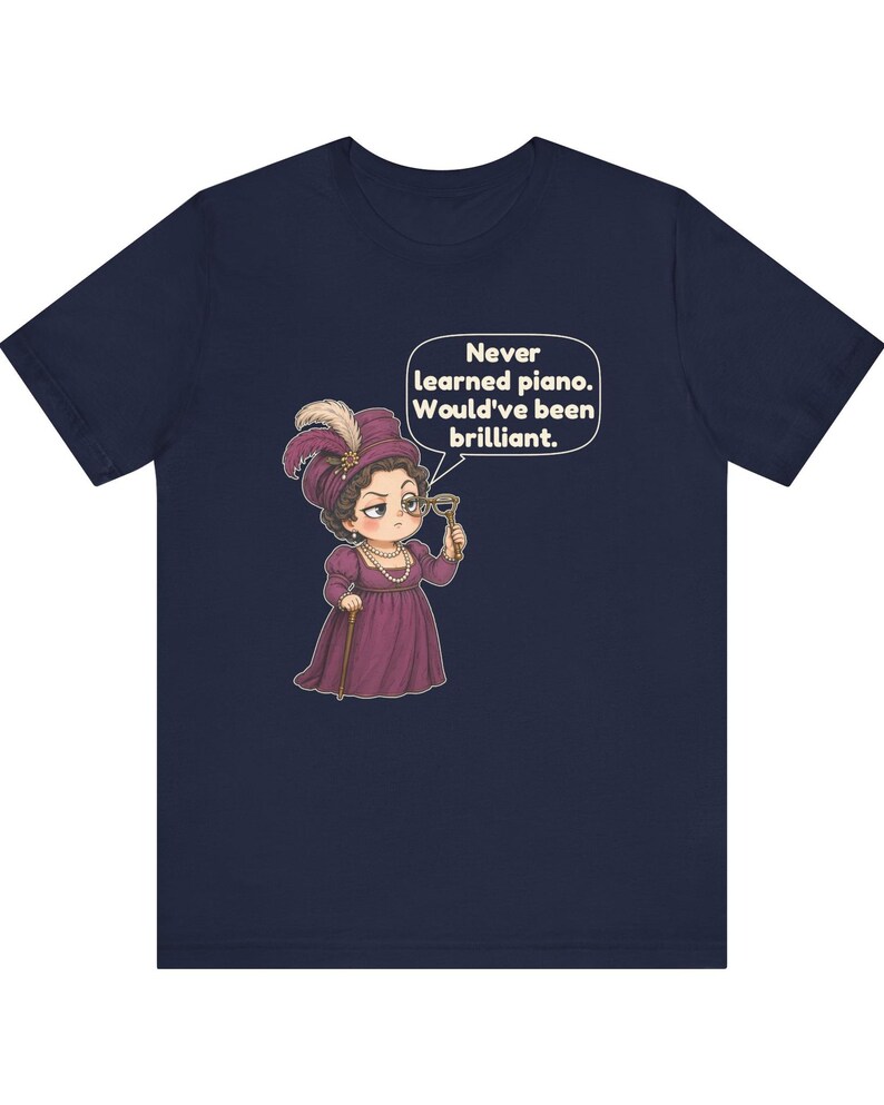 May include: A navy blue t-shirt featuring a cartoon illustration of a person in a purple Victorian-style dress and hat, holding a monocle. A speech bubble above the figure contains the text: Never learned piano. Would've been brilliant.
