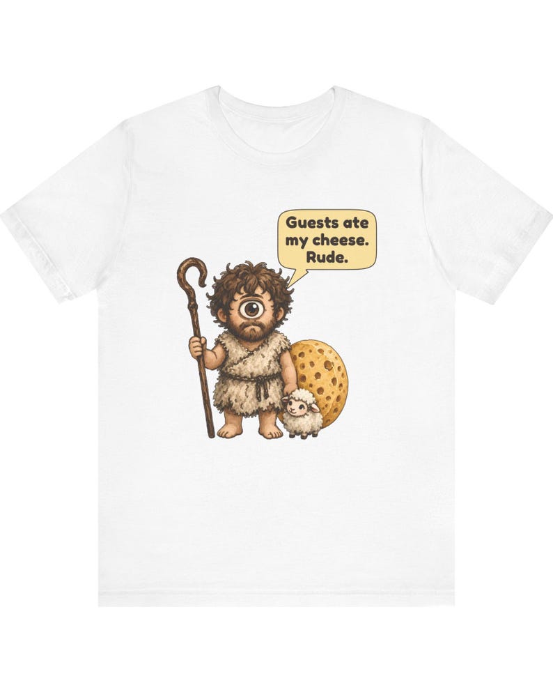 May include: A white t-shirt featuring a graphic of a cyclops wearing a fur tunic, holding a wooden staff, and standing next to a small sheep and a large wheel of cheese. A speech bubble above the cyclops reads, Guests ate my cheese. Rude.