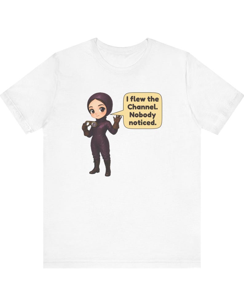 Puede incluir: Una camiseta blanca con un personaje de dibujos animados vestido con un traje de vuelo y casco de color morado oscuro, sosteniendo unas gafas. Un bocadillo amarillo junto al personaje contiene el texto: I flew the Channel. Nobody noticed.