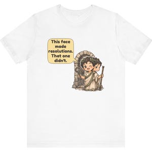 K&ouml;nnte beinhalten: Ein wei&szlig;es T-Shirt mit einer Grafik einer r&ouml;mischen Figur mit zwei Gesichtern, die einen Lorbeerkranz und eine Toga tr&auml;gt und vor einem Steinbogen steht. Ein Gesicht zwinkert und h&auml;lt einen Schl&uuml;ssel, das andere sieht m&uuml;rrisch aus. Eine Sprechblase besagt: This face made resolutions. That one didn't.