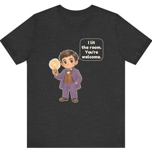 Może przedstawiać: Ciemnoszary melanżowy t-shirt z rysunkową ilustracją postaci w fioletowym garniturze i brązowej kamizelce, trzymającej świecącą żar&oacute;wkę. Dymek obok postaci zawiera tekst: I lit the room. You're welcome.