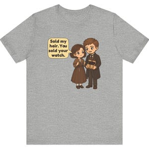 May include: A heather gray t-shirt featuring a cartoon illustration of two people in brown clothing. One person holds a small box, and a speech bubble contains the text: Sold my hair. You sold your watch.