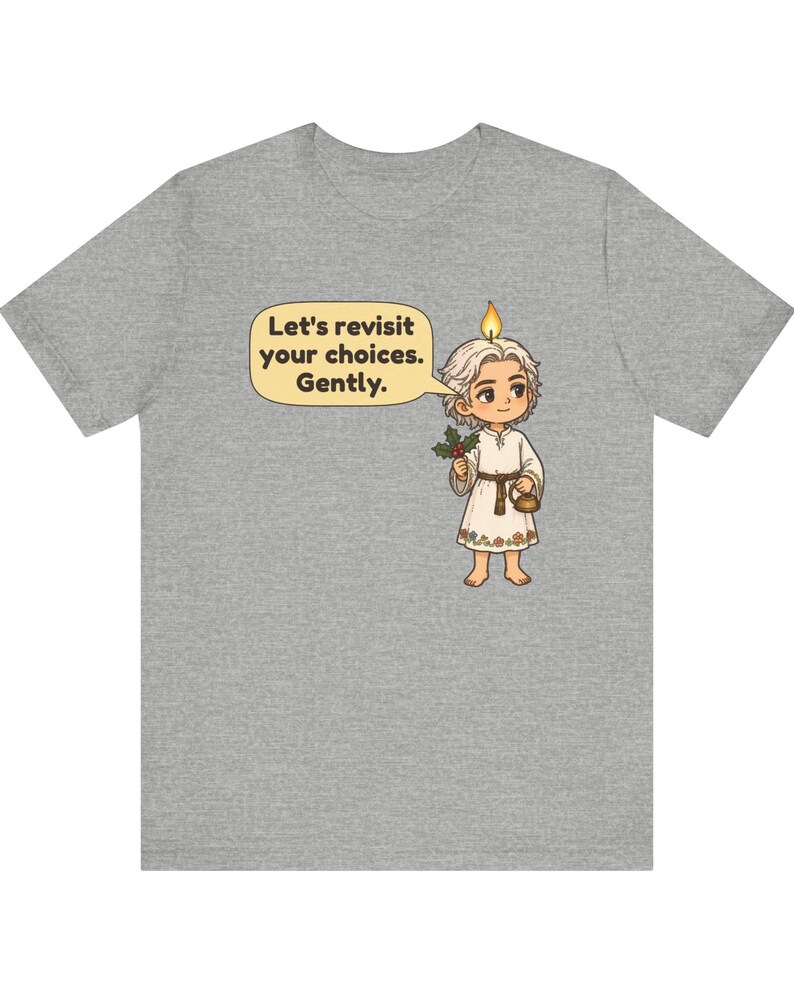 May include: A heather gray t-shirt featuring a cartoon character with a candle flame on their head, holding a sprig of holly and a small kettle. A speech bubble contains the text: Let's revisit your choices. Gently. The character wears a white tunic.