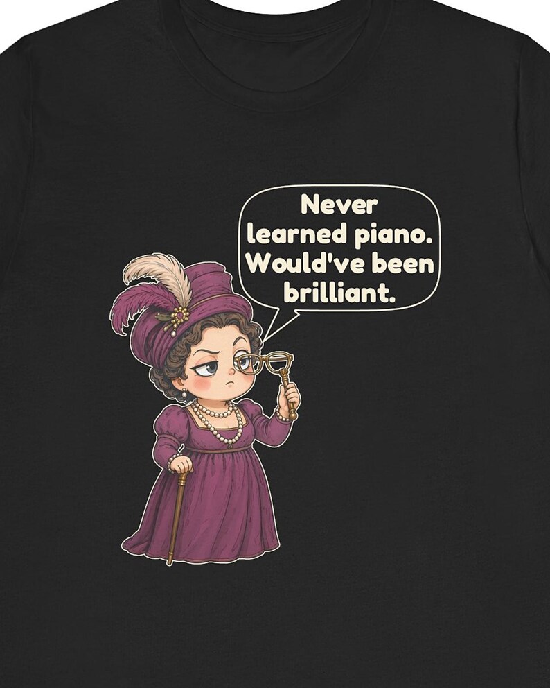 May include: A black t-shirt featuring a cartoon illustration of a person in a purple Victorian-style dress and hat, holding a monocle. A speech bubble above contains the text: Never learned piano. Would've been brilliant.