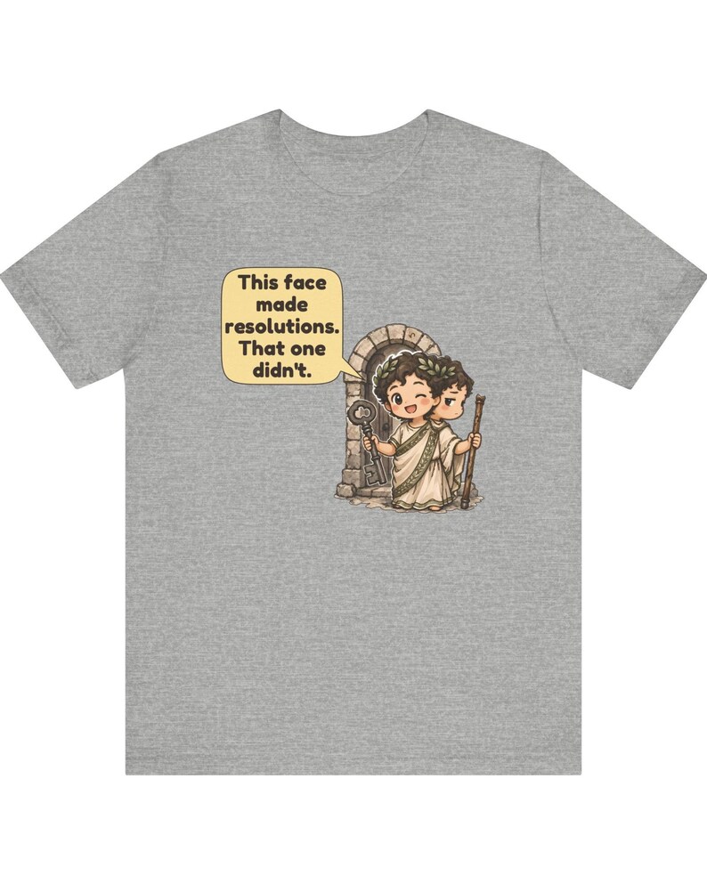 K&ouml;nnte beinhalten: Ein graues meliertes T-Shirt mit einer Grafik einer r&ouml;mischen Figur mit zwei Gesichtern, die einen Lorbeerkranz tr&auml;gt und einen Schl&uuml;ssel sowie einen Stab vor einem Torbogen h&auml;lt. Eine Sprechblase enth&auml;lt den Text: This face made resolutions. That one didn't.
