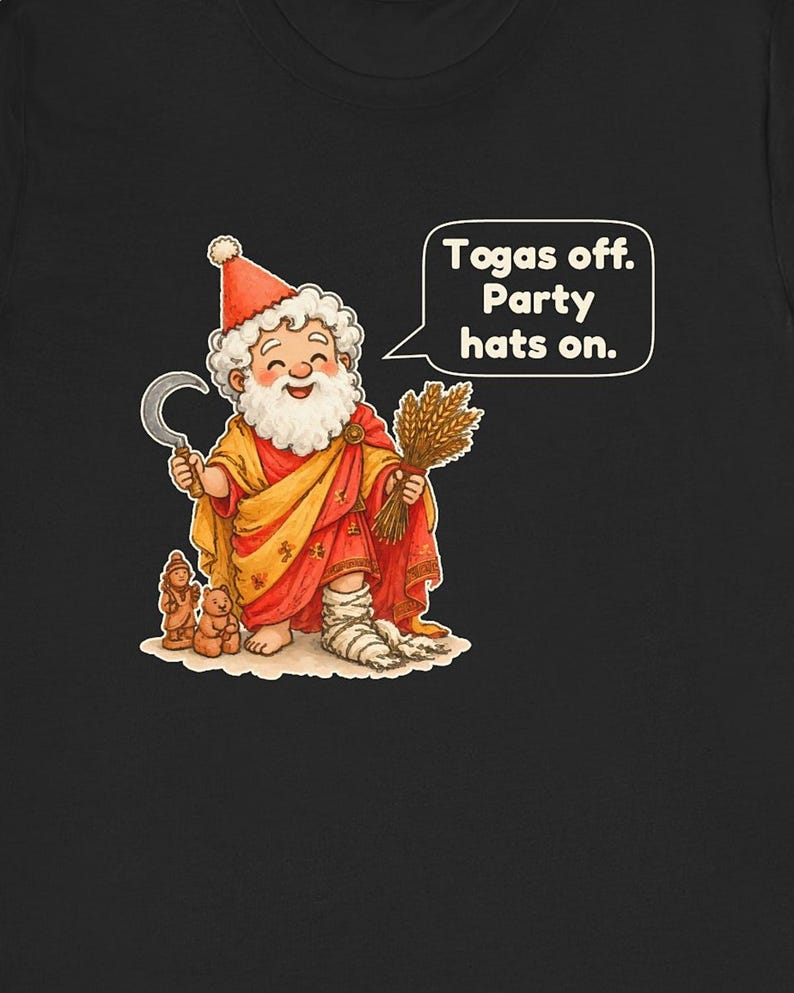 May include: A black t-shirt featuring a cartoon illustration of a bearded figure wearing a red party hat, a yellow and red toga, and white leg wraps. The figure holds a sickle and wheat, with a speech bubble that reads: Togas off. Party hats on.